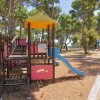 Parco giochi con scivolo e alberi intorno.