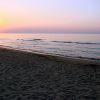 Tramonto sul mare visto da una spiaggia sabbiosa.