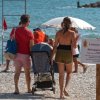 Famiglia cammina su una spiaggia di ciottoli.