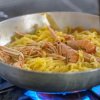 Pasta con crostacei in padella su fornello acceso.