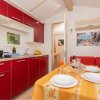 Cucina rossa con tavolo apparecchiato e divano arancione.