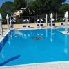 Piscina all'aperto con sedie a sdraio e ombrelloni.