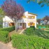 Casa con giardino, sedie e tavolo tra cespugli.