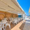 Ristorante all'aperto sulla spiaggia con tavoli e sedie bianche.