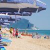 Spiaggia con ombrelloni blu e persone che camminano sulla sabbia.