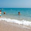 Persone nuotano e giocano in mare, vicino alla riva.