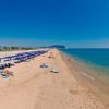 Spiaggia con ombrelloni blu, mare e cielo limpidi.