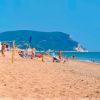 Spiaggia affollata con vista su un promontorio lontano.