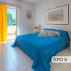 Camera con letto blu, tende gialle e quadro.