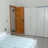 Una camera da letto con un letto singolo e un armadio bianco. Una porta di legno è aperta.