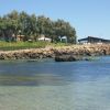 Costa con rocce, alberi e edifici con vista sul mare calmo.
