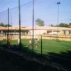 Campo da calcio all'aperto con rete di recinzione e giocatori.