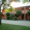 Edificio a due piani con alberi e cortile.