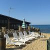 Spiaggia con sdraio bianche e ombrellone verde a righe, vicino al mare.