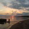 Spiaggia al tramonto con due persone e una canoa vicino alla riva.
