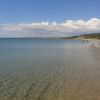 Spiaggia con mare calmo e cielo nuvoloso.