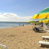 Spiaggia con lettini e ombrelloni giallo-verdi, persone sulla riva.