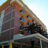Edificio in muratura a più piani con balconi e palme.