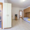 Stanza con doccia, armadio, letto coperto da lenzuola blu e TV su mobile di legno.