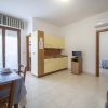 Cucina con angolo cottura, tavolo apparecchiato, porta finestra con tende a righe.