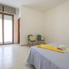 Camera da letto luminosa con letto matrimoniale, due sedie e porta finestra con tende a righe.