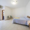 Stanza ampia con letto matrimoniale, due sedie, porta finestra e illuminazione a soffitto.