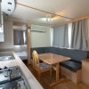 Interno di una casa mobile con cucina, tavolo da pranzo e area salotto.