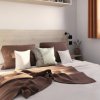 Camera da letto con letto matrimoniale, cuscini morbidi e coperta marrone.