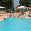 Piscina all'aperto con bagnanti e ombrelloni su un solarium in legno.