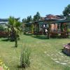 Giardino con percorsi erbosi, fiori, alberi e panchine sotto pergolati.