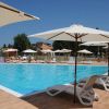 Piscina all'aperto con lettini bianchi sotto ombrelloni grandi.