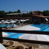 Piscina scoperta con ombrelloni bianchi e struttura in legno sullo sfondo.