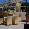 Una terrazza con tavoli e sedie gialle sotto tende ombreggianti.