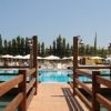 Un pontile di legno porta a una piscina, circondata da ombrelloni bianchi.