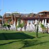 Una struttura di legno con terrazza e ombrelloni bianchi su un prato verde.