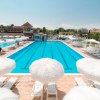 Piscina all'aperto con ombrelloni bianchi e lettini.