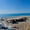 Lungomare con lettini e ombrelloni bianchi, strutture su una spiaggia.