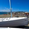 Barca a vela su una spiaggia affollata con ombrelloni e persone.