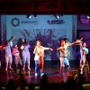 Spettacolo teatrale con persone che ballano su un palco illuminato.