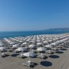 Spiaggia con file di ombrelloni bianchi.