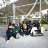 Persone in divise coordinate posano vicino a piccoli veicoli elettrici sotto una struttura aperta.