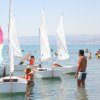 Bambini e adulti con piccole barche a vela in mare.