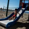 Bambino scende da uno scivolo sulla spiaggia.