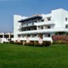 Hotel bianco con giardino verde.