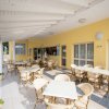 Area esterna con sedie e tavoli sotto una tettoia, accanto a un edificio giallo.