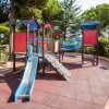 Parco giochi con scivoli e strutture colorate per bambini circondato da alberi.