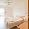 Camera da letto luminosa con due letti singoli, ventilatore a soffitto e porta finestra.