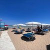 Spiaggia sabbiosa con lettini e ombrelloni bianchi, vista mare.