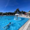 Piscina con fontana a fungo. Persone che nuotano e si rilassano intorno.