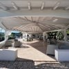 Struttura coperta con divani e poltrone all'aperto, sotto un soffitto stilizzato.